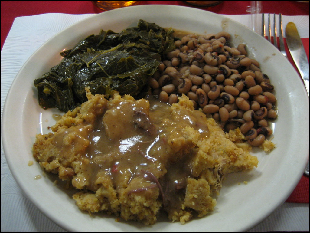 A plate of tender collard greens with black-eyed peas and cornbread dressing smothered in gravy